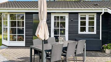A house with a patio, a table with chairs, and a covered umbrella.