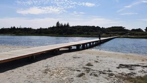 A wooden pier extending into a body of water, with a person standing at the end. - Holiday Home in Hadsund (Hadsund)