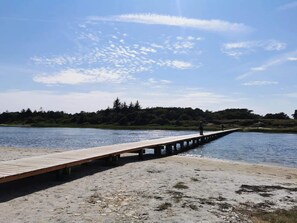 A wooden pier extending into a body of water, with a person standing at the end. - Holiday Home in Hadsund (Hadsund)