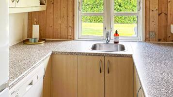 A kitchen with wooden cabinets, a granite countertop, a stainless steel sink, and a window with a view of a green lawn.