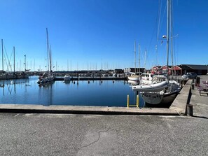 A marina with boats docked, a clear sky, and a building in the background.