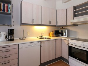 A modern kitchen with light wood cabinets, a built-in microwave, a coffee maker, and a dishwasher. - 6 Person Holiday Home in Hadsund (Hadsund)