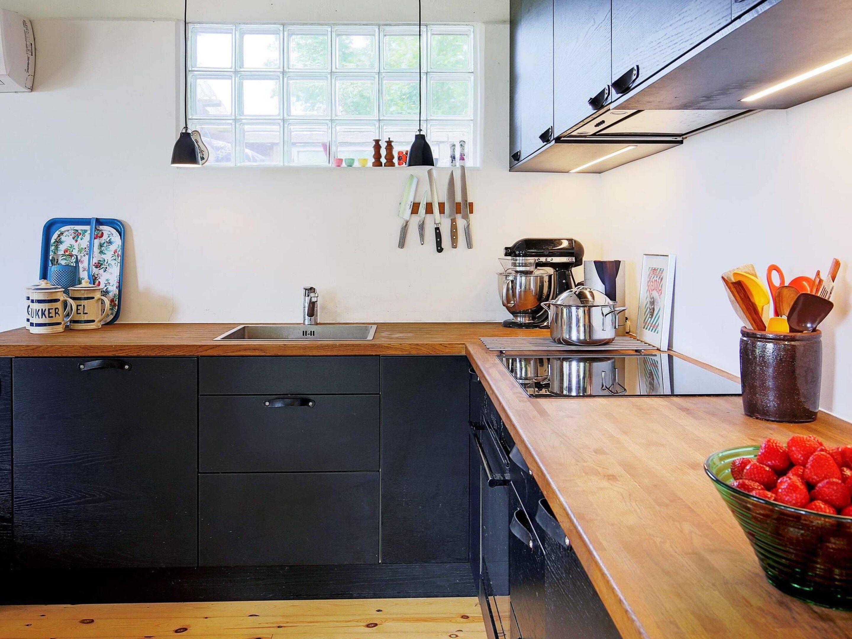 Een moderne keuken met een houten aanrecht, een spoelbak en diverse keukenapparaten.