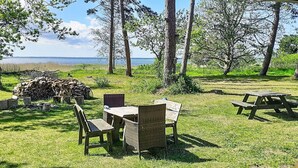 An outdoor seating area with wicker furniture, a picnic table, and a pile of firewood. - 5 Person Holiday Home in Jaegerspris (Jægerspris)