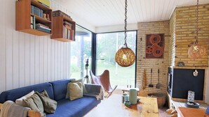 A cozy living room with a blue sofa, a wooden coffee table, and a fireplace. - 5 Person Holiday Home in Jaegerspris (Jægerspris)