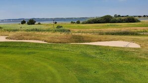 A golf course with sand bunkers, a flagstick, and a clear view of the water in the background. - 5 Person Holiday Home in Jaegerspris (Jægerspris)