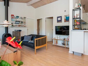 A modern living room with a wooden sofa, a television, and a bookshelf. - 4 Star Holiday Home in Glesborg (Glesborg)