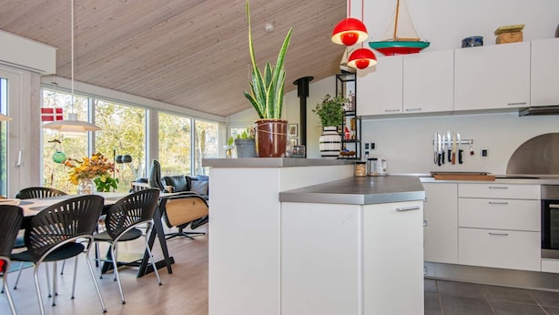 Een moderne keuken met witte kasten, een centraal eiland en een eetgedeelte met zwarte stoelen.