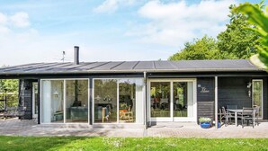 Een moderne woning met een terras, grote glazen deuren en een schoorsteen.