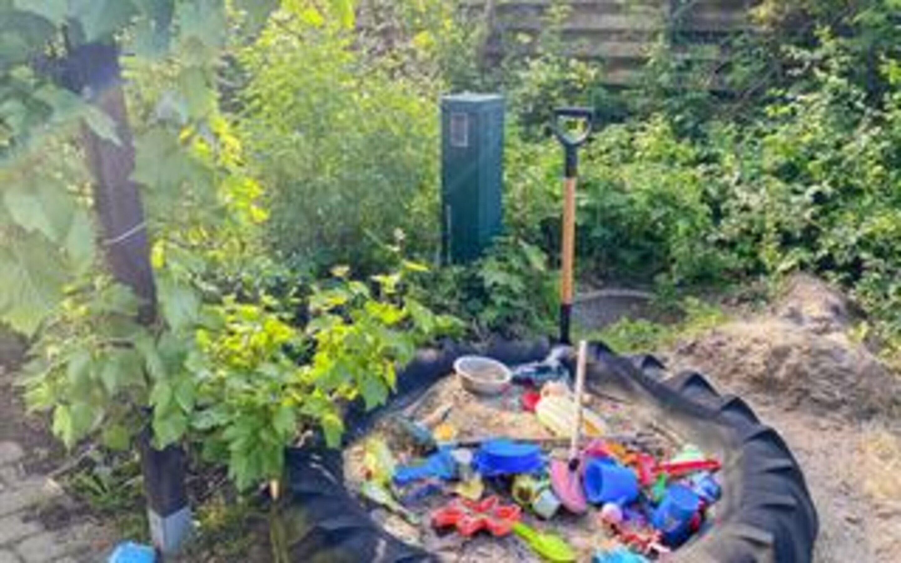 A garden with a raised bed, a green utility box, and a metal pole.