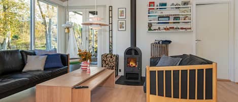 A modern living room with a sofa, a wooden coffee table, a fireplace, and a bookshelf.