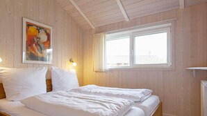 A room with a bed, a painting on the wall, and a window. - Holiday Home in GrÃ¶mmitz (Groemitz)