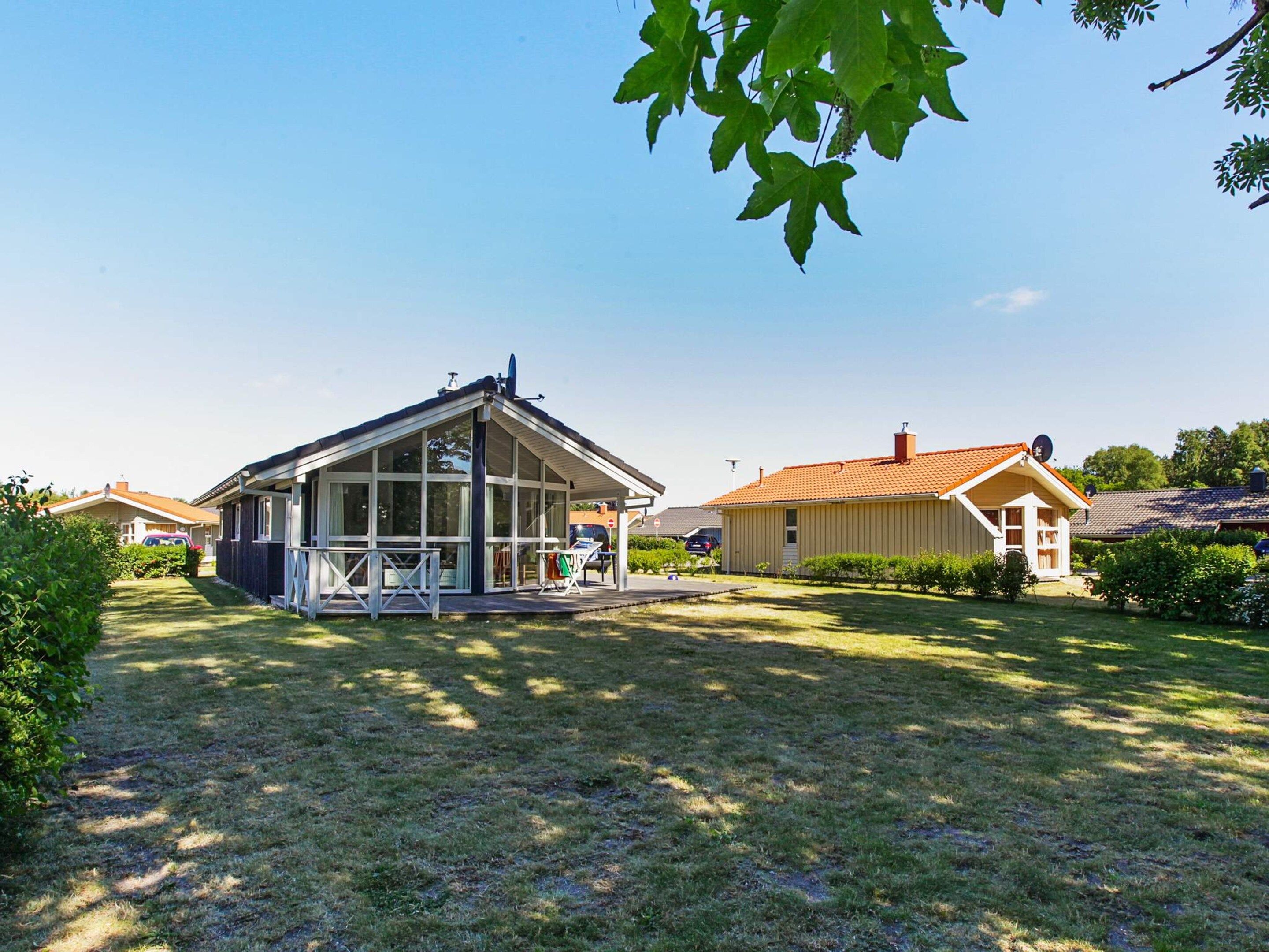 A residential property with a large glass-covered structure, a fenced yard, and a neighboring house with a tiled roof.