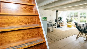 A wooden staircase leading to a spacious living area with a dining table, chairs, and a television.
