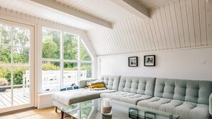 A cozy living room with a large window, a glass coffee table, and a grey sofa.