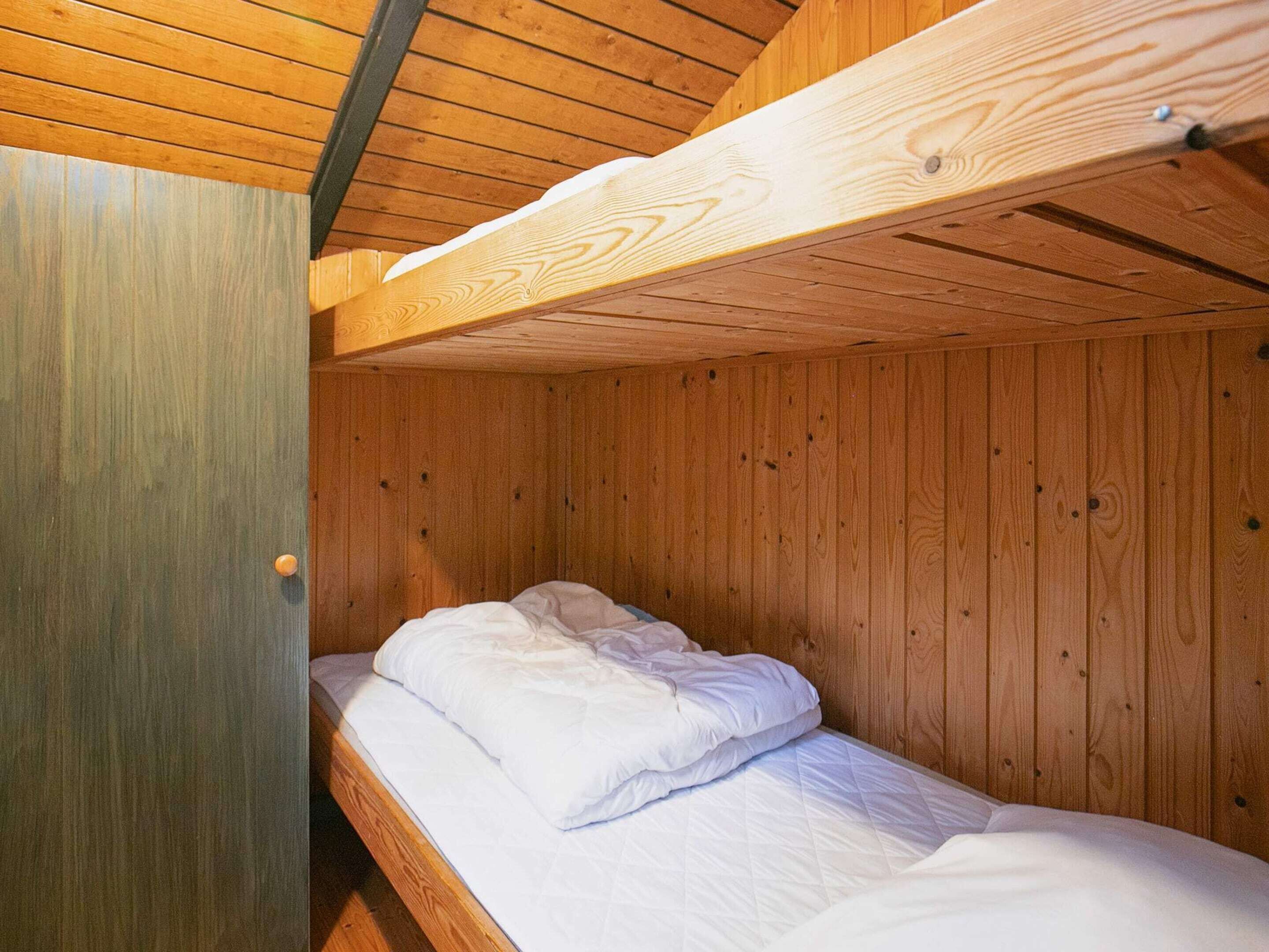 A bunk bed with wooden walls and a metal door.