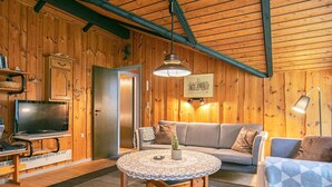 A cozy cabin interior with a wooden interior, a sofa, a round table, and a television. - 6 Person Holiday Home in Lokken (Lokken)