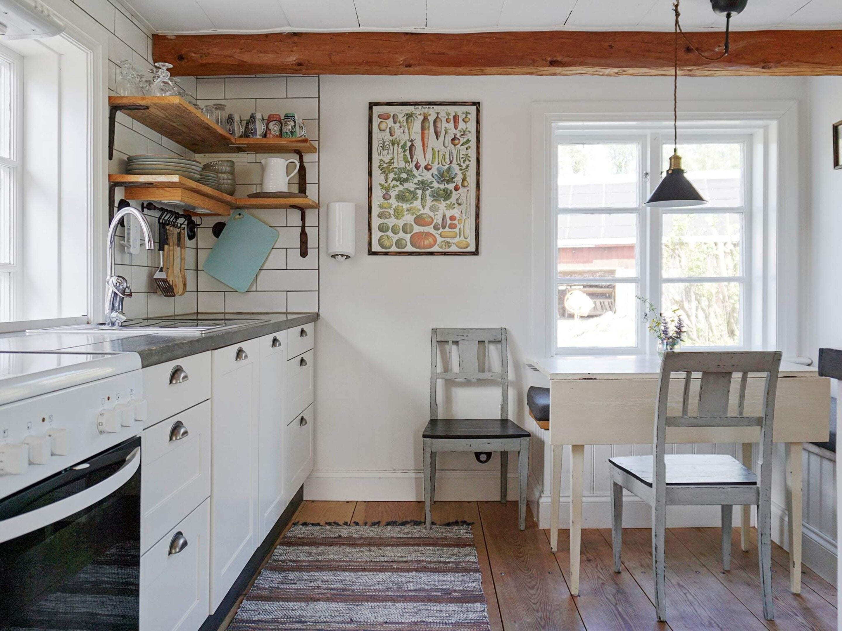 A kitchen with white cabinets, a wooden countertop, a hanging light fixture, and a window with a view of the outdoors.