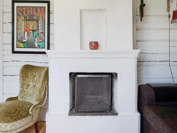 A room with a white fireplace, a framed poster on the wall, and two chairs.