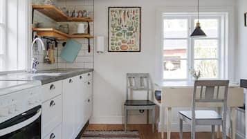 Une cuisine avec des armoires blanches, un plan de travail en bois, un luminaire suspendu et une fenêtre donnant sur l’extérieur.