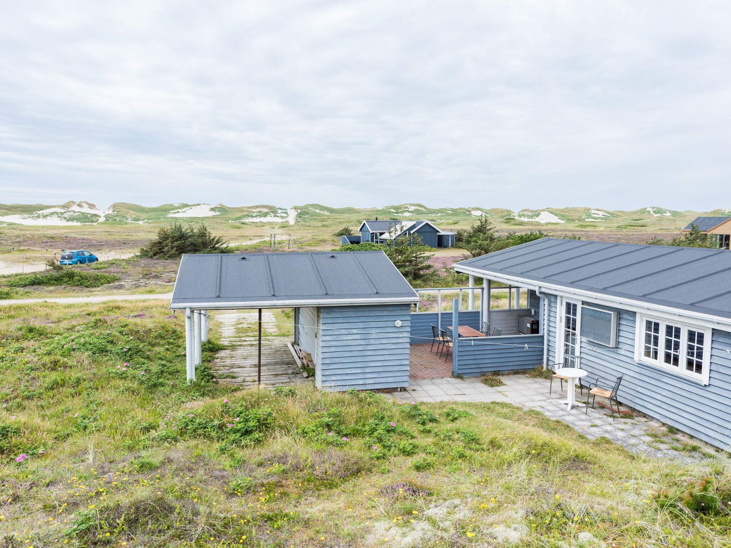 A coastal house with a covered patio, a small deck, and a view of the dunes.