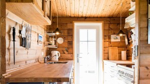 Eine Küche mit Holzwänden, einem Spülbecken, einem Wasserkocher und einem Kühlschrank.