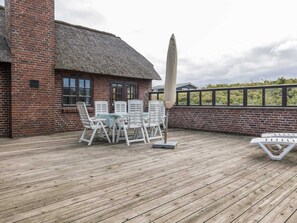 Relax on the deck with a round table and lounge chair, surrounded by lush greenery.