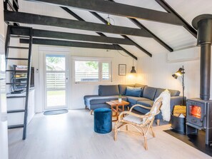 Een gezellige woonkamer met een bank, een fauteuil, een tafel en een houtkachel.