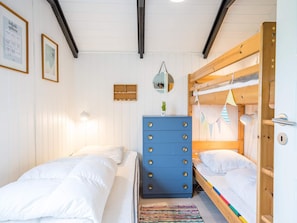 A room with two beds, a dresser, a mirror, and a small shelf with items.