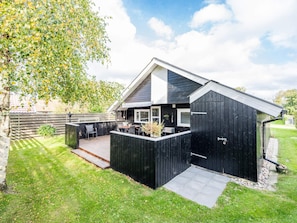 A modern house with a deck, a garage, and a well-maintained lawn.