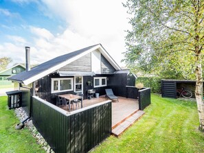 Een modern huis met een terras, een patio en een kleine tuinhuisje.