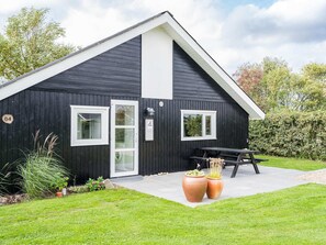 A black building with a white door, two windows, and a picnic table.