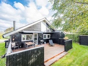 A modern house with a deck, outdoor seating, and a chimney.