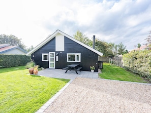 A two-story house with a black exterior, a front door, and a small patio area with a table and chairs.