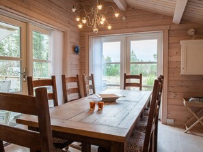 Un interior de madera con una mesa de comedor, sillas y una araña.