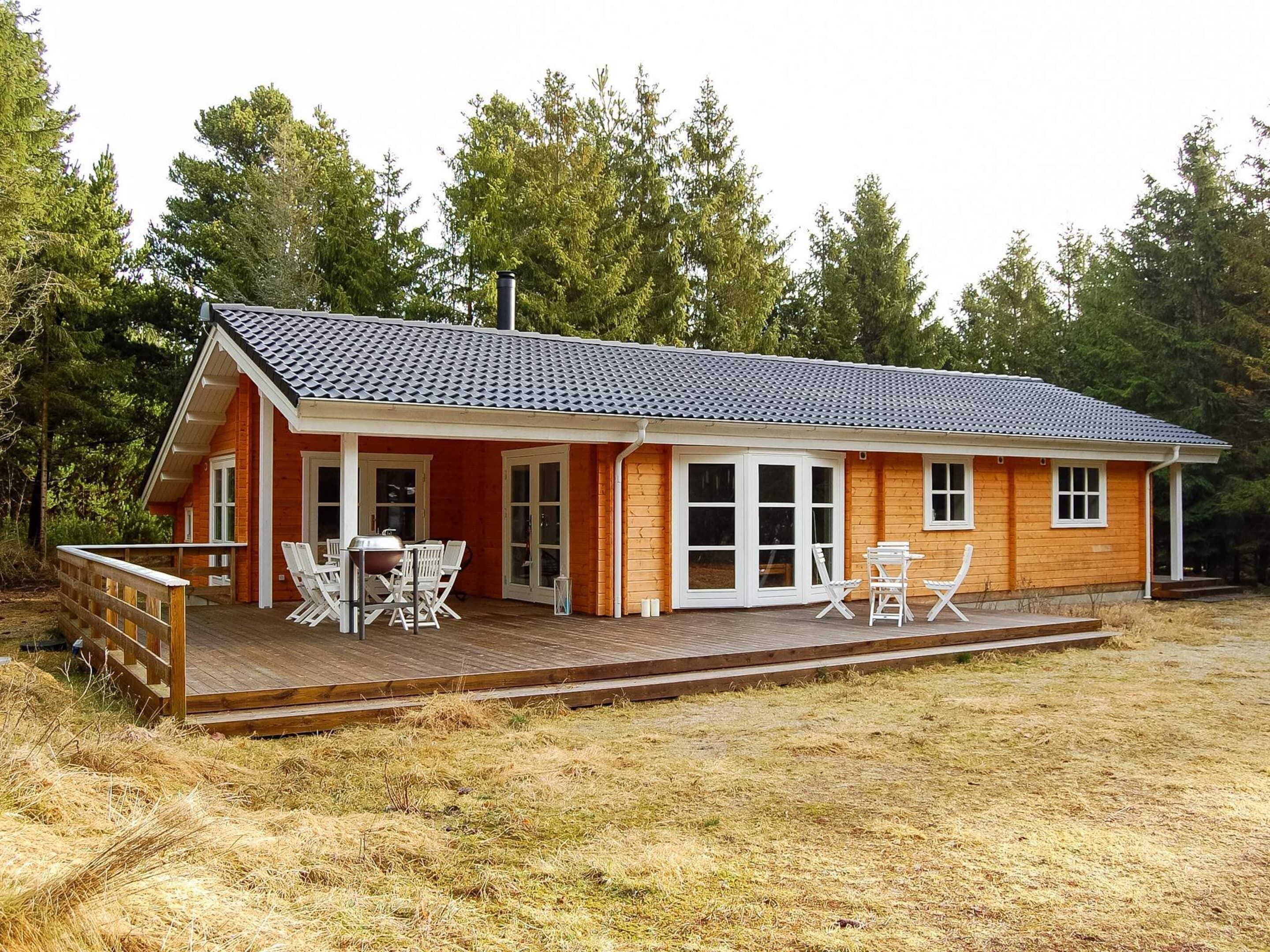 A two-story wooden house with a covered patio, large windows, and a chimney.