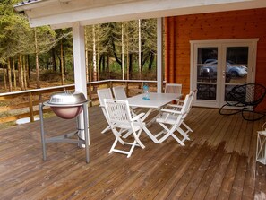 An outdoor patio with a table and chairs, a grill, and a view of trees. - 4 Star Holiday Home in Norre Nebel (Norre Nebel)