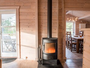 A wood-burning stove in a cabin with a dining area and a view of the outdoors. - 6 Person Holiday Home in Norre Nebel (Norre Nebel)