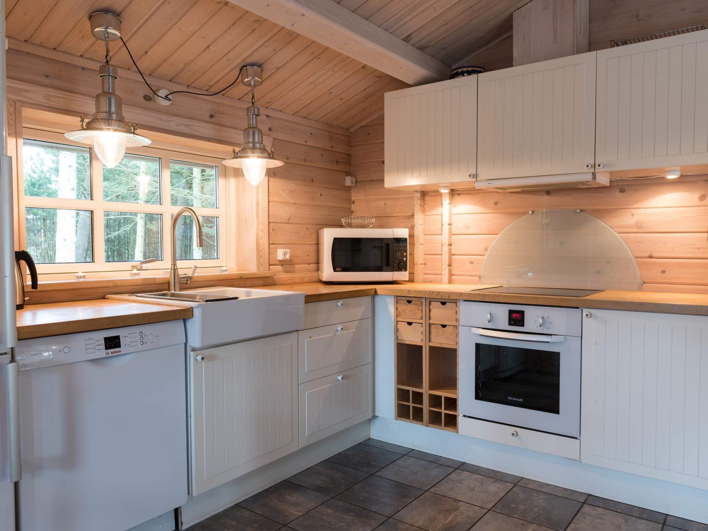 A modern kitchen with white cabinetry, a Bosch dishwasher, a microwave, and a Brandt oven.