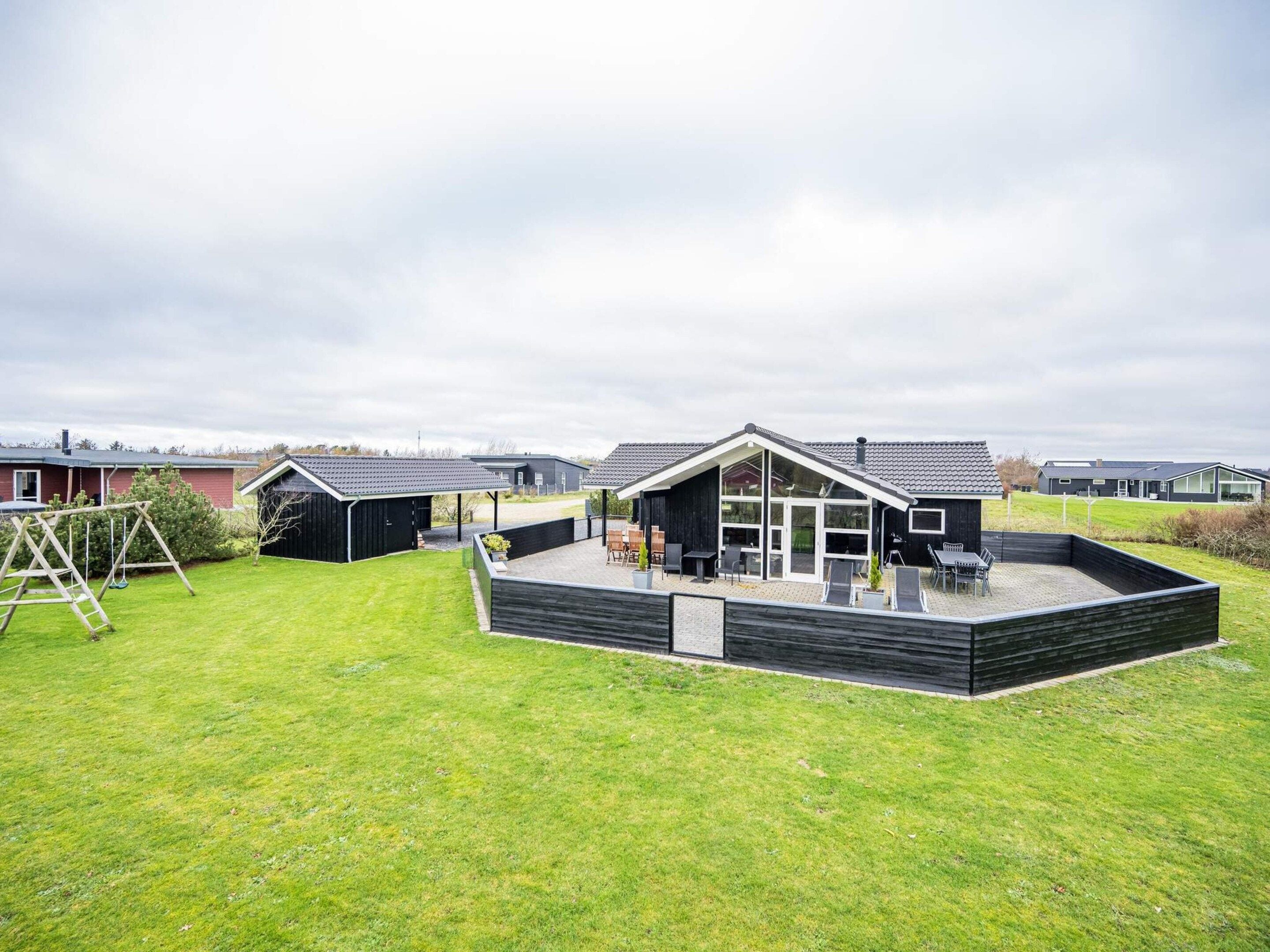 A residential property with a patio area, a swing set, and a covered outdoor seating area.