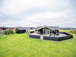 A residential property with a patio area, a swing set, and a covered outdoor seating area.