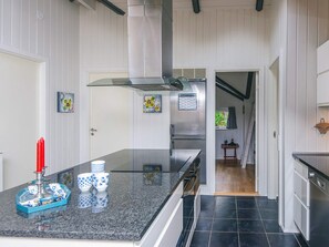 A modern kitchen with a central island, stainless steel appliances, and a view into the dining area. - 4 Star Holiday Home in Fano (Fano)