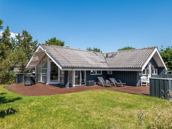 A two-story house with a sloped roof, a covered patio area, and a fenced backyard.
