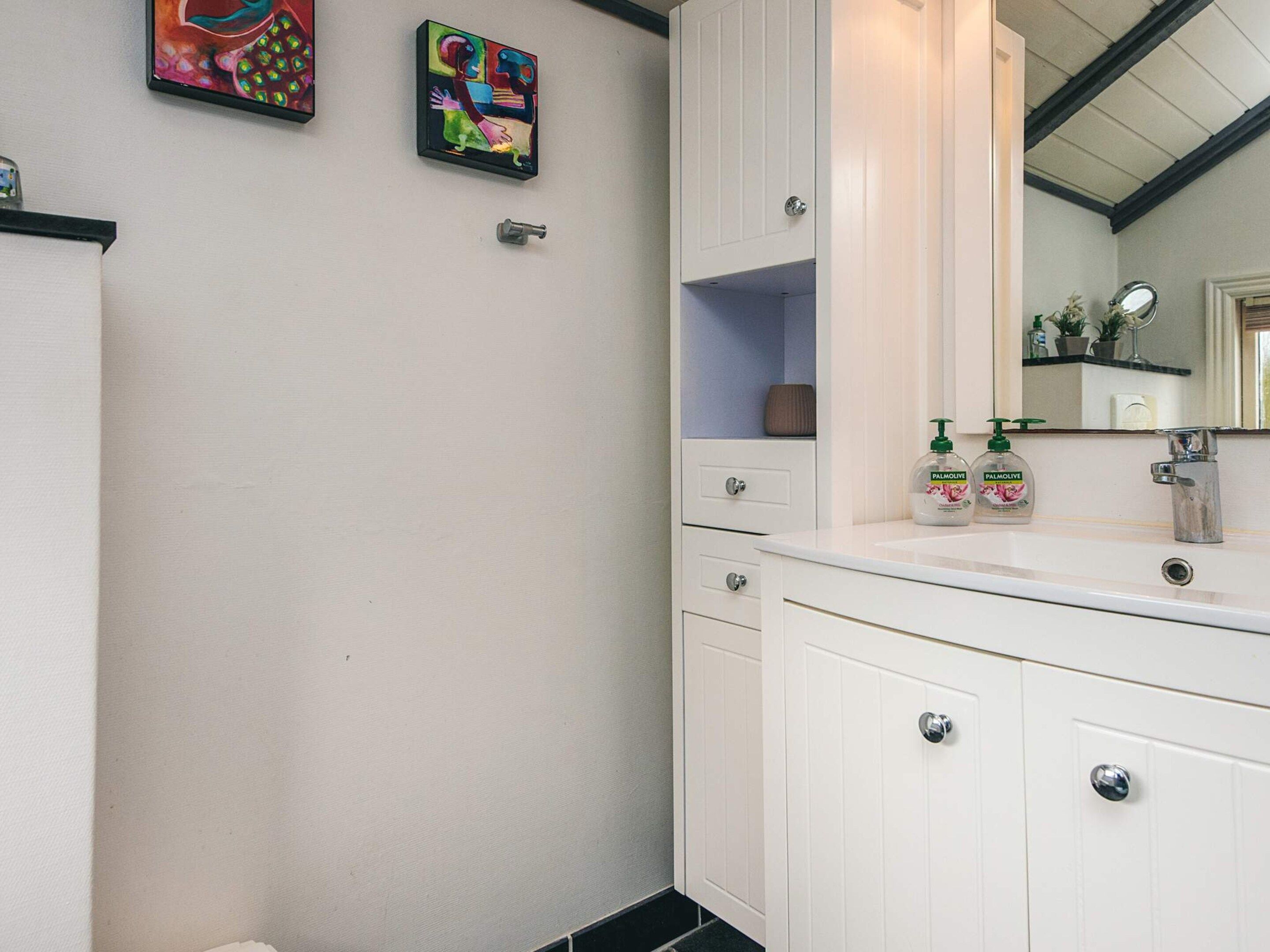 A bathroom with a white vanity, a mirror, and two bottles of Palmolive soap.