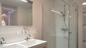 A modern bathroom with a glass-enclosed shower, a double sink vanity, and a large mirror. - Apartment in Scheveningen With Harbor View (The Hague)