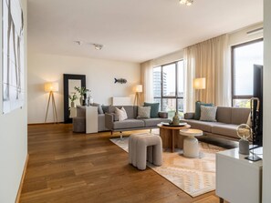 A modern living room with a sofa set, a coffee table, and a lamp. - Luxury Apartment With a View (The Hague)