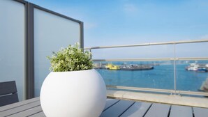 A white pot with green foliage on a balcony with a view of the sea and boats. - Luxury Apartment With a View (The Hague)