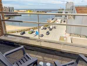 A balcony with a view of a parking lot and beach. - Luxury Apartment With a View (The Hague)