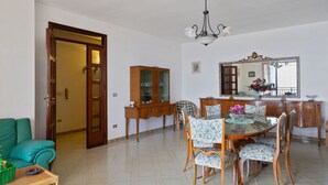 A dining area with a round table, floral chairs, a wooden cabinet, and a mirror above the table.