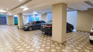 Un parking avec un sol carrelé à motifs et plusieurs voitures stationnées.